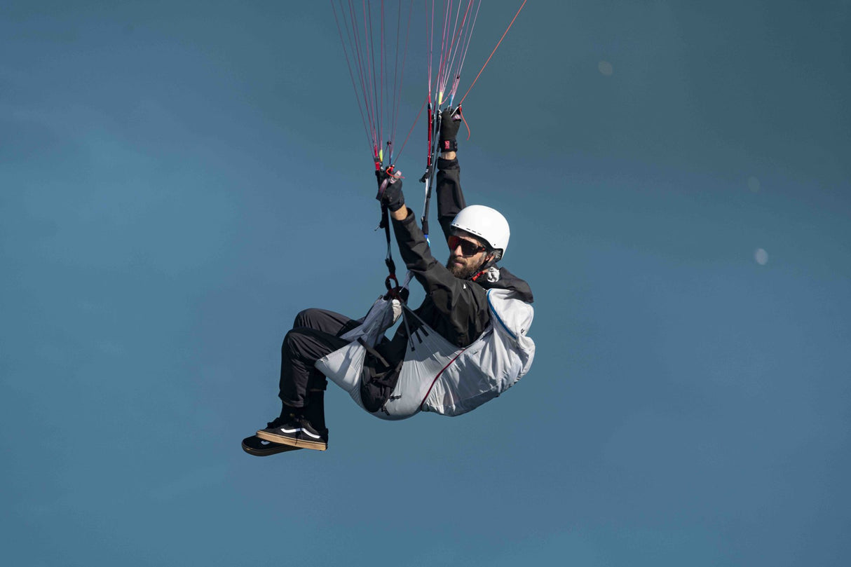Person hand gliding against a clear blue sky