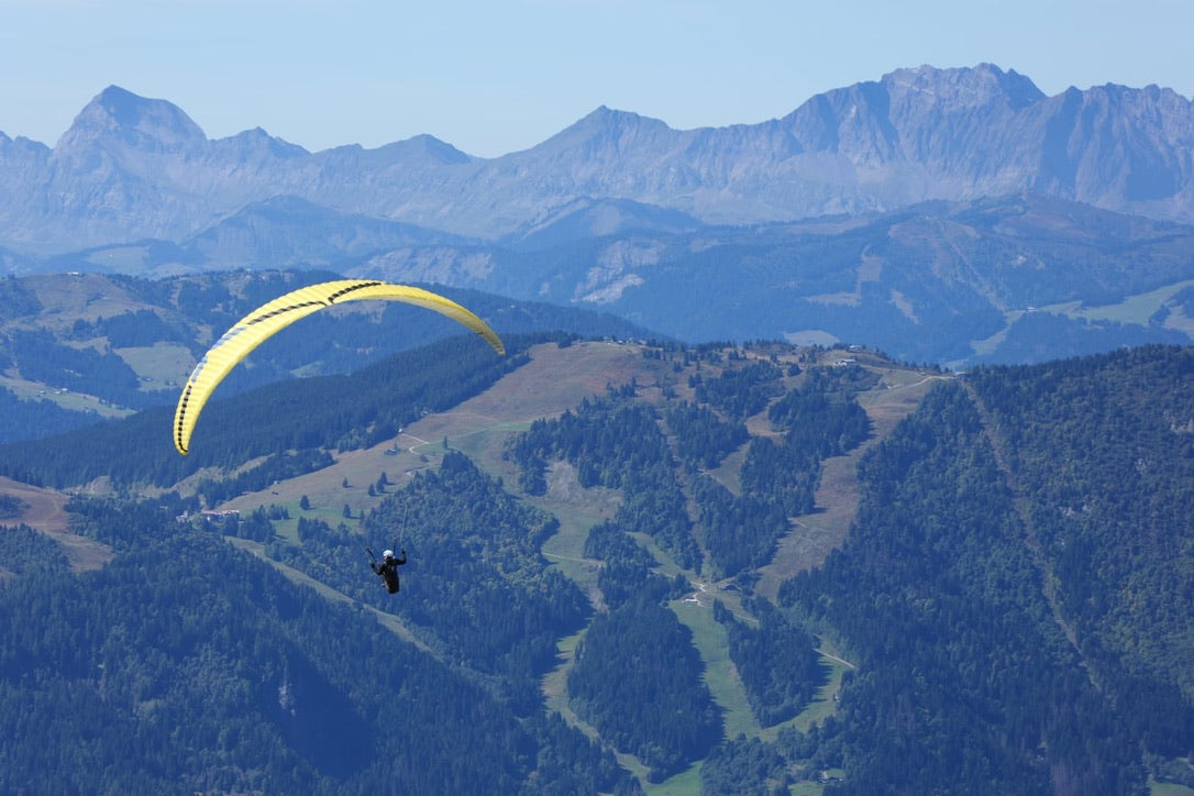 Person paragliding with mountains in the background