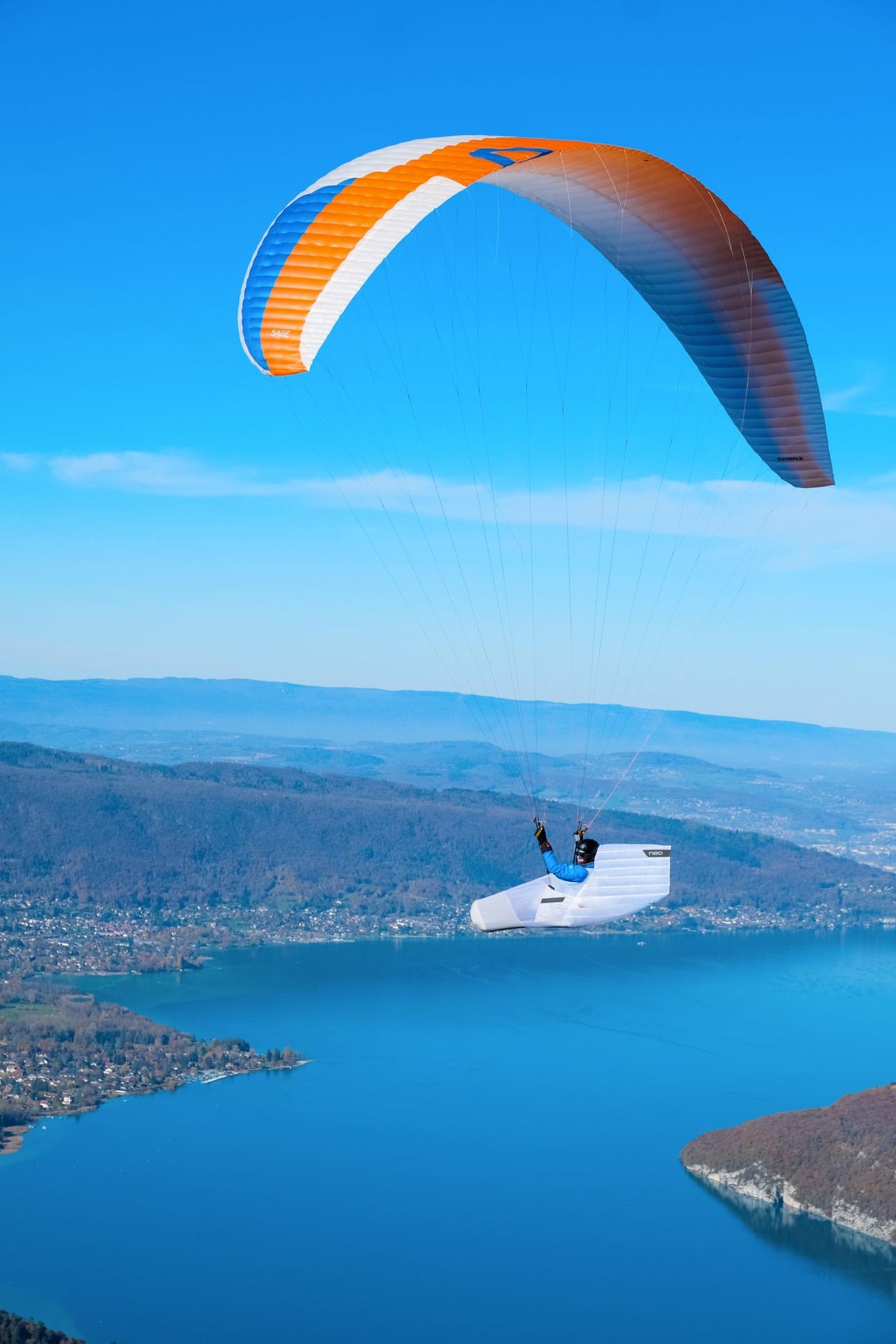 Person paragliding over a lake with a clear blue sky