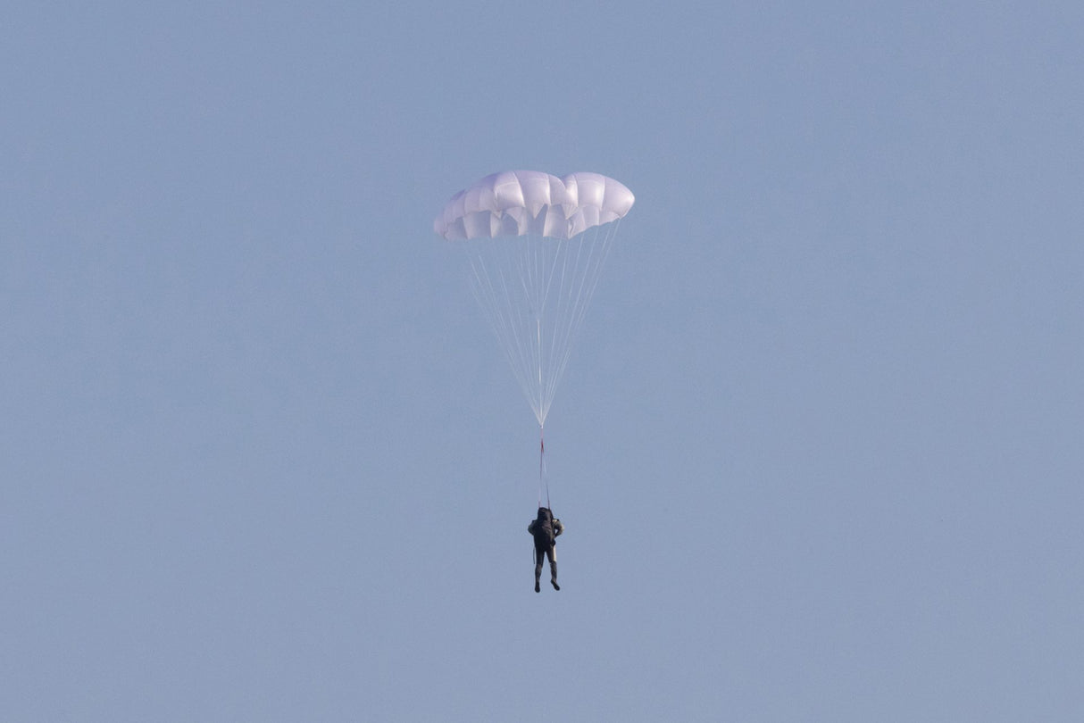 Person parachuting against a clear blue sky