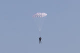 Person parachuting against a clear blue sky