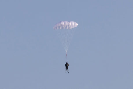 Person parachuting against a clear blue sky