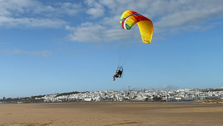 man landing a parajet on a beach