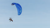 Person flying paratrike in a blue sky
