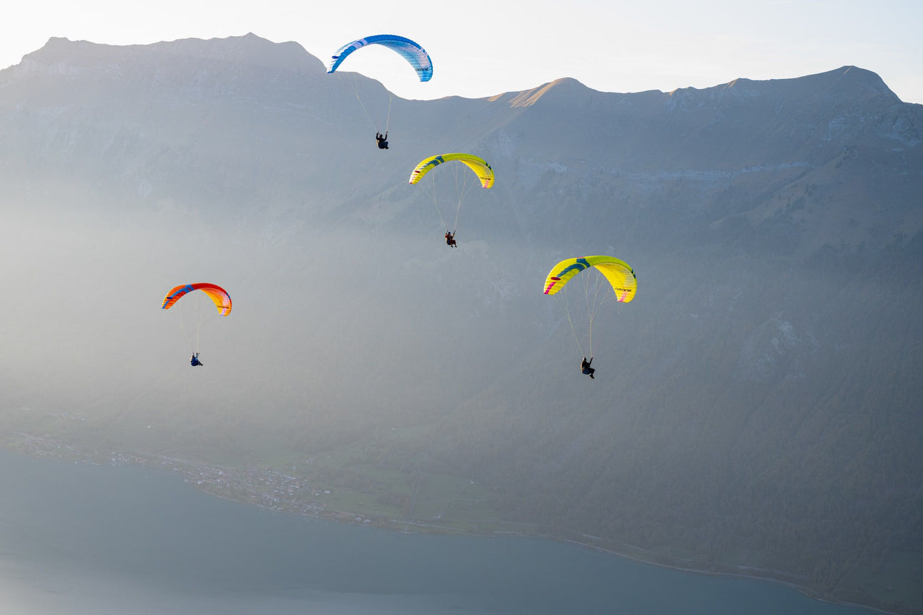 four paramotors flying through mist in front of hills