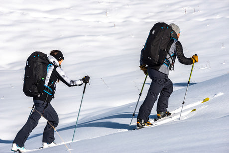 Two people cross-country skiing on a snowy landscape