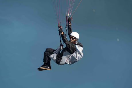 Person hand gliding against a clear blue sky