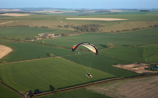 man flying paramotor over fields