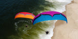 two paramotors flying over the shore