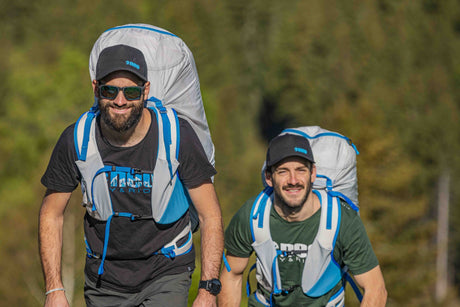 Two men hiking with neo litebag harness in a forested area