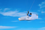 Person hand gliding in a clear blue sky with a white paraglider.